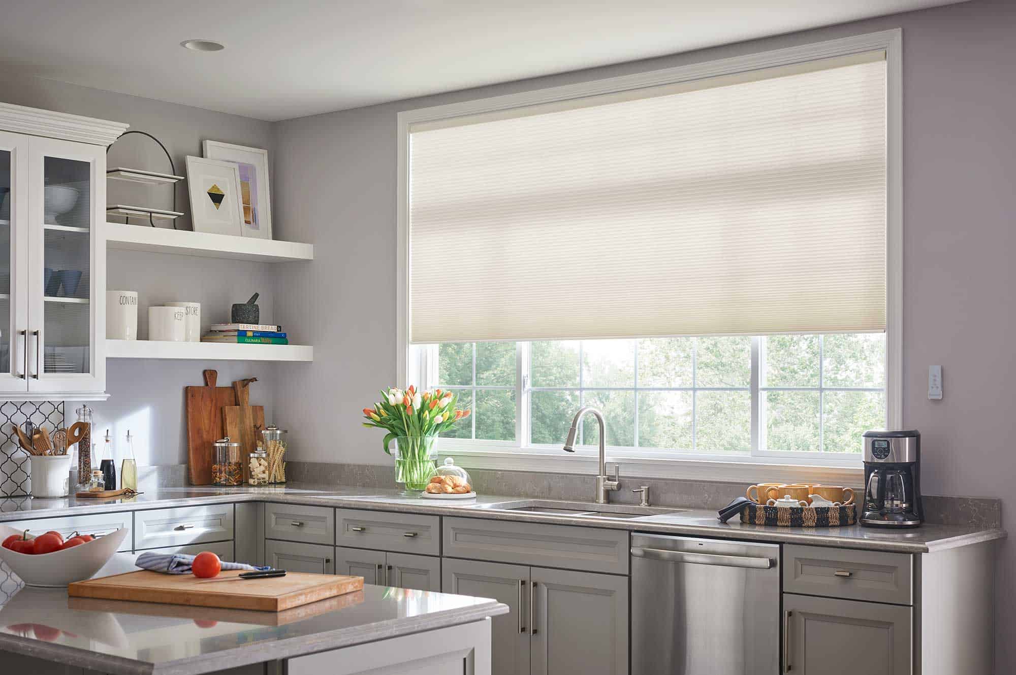 Window Shades 13 Honeycomb shades in a modern kitchen with grey cabinets and large window.