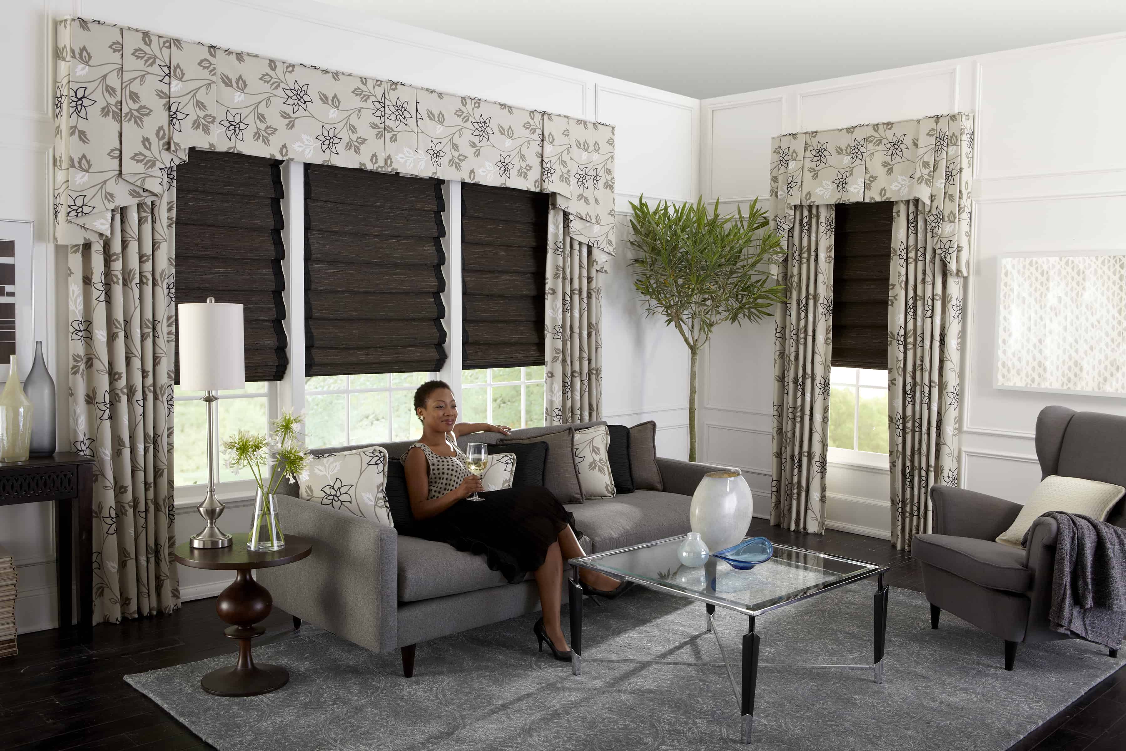 lady enjoying drink by tailored window treatments
