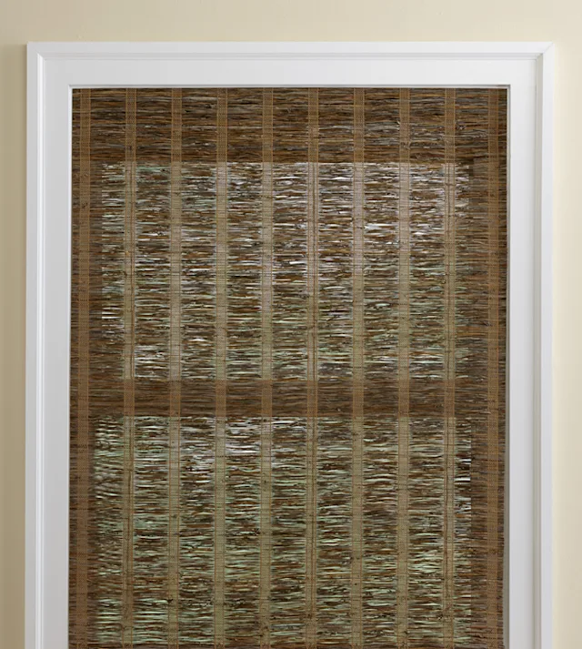 Waterfall-style natural woven shade with a clean flush mount and back valance concealing hardware, showcased on a display in a Nicholasville, KY showroom, framed by sleek wooden trim and soft spotlighting.