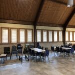 Interior view of Trinity Methodist Church in Lexington, KY, featuring white plantation shutters installed on standard-sized windows, framed by a softly lit room with warm wooden accents