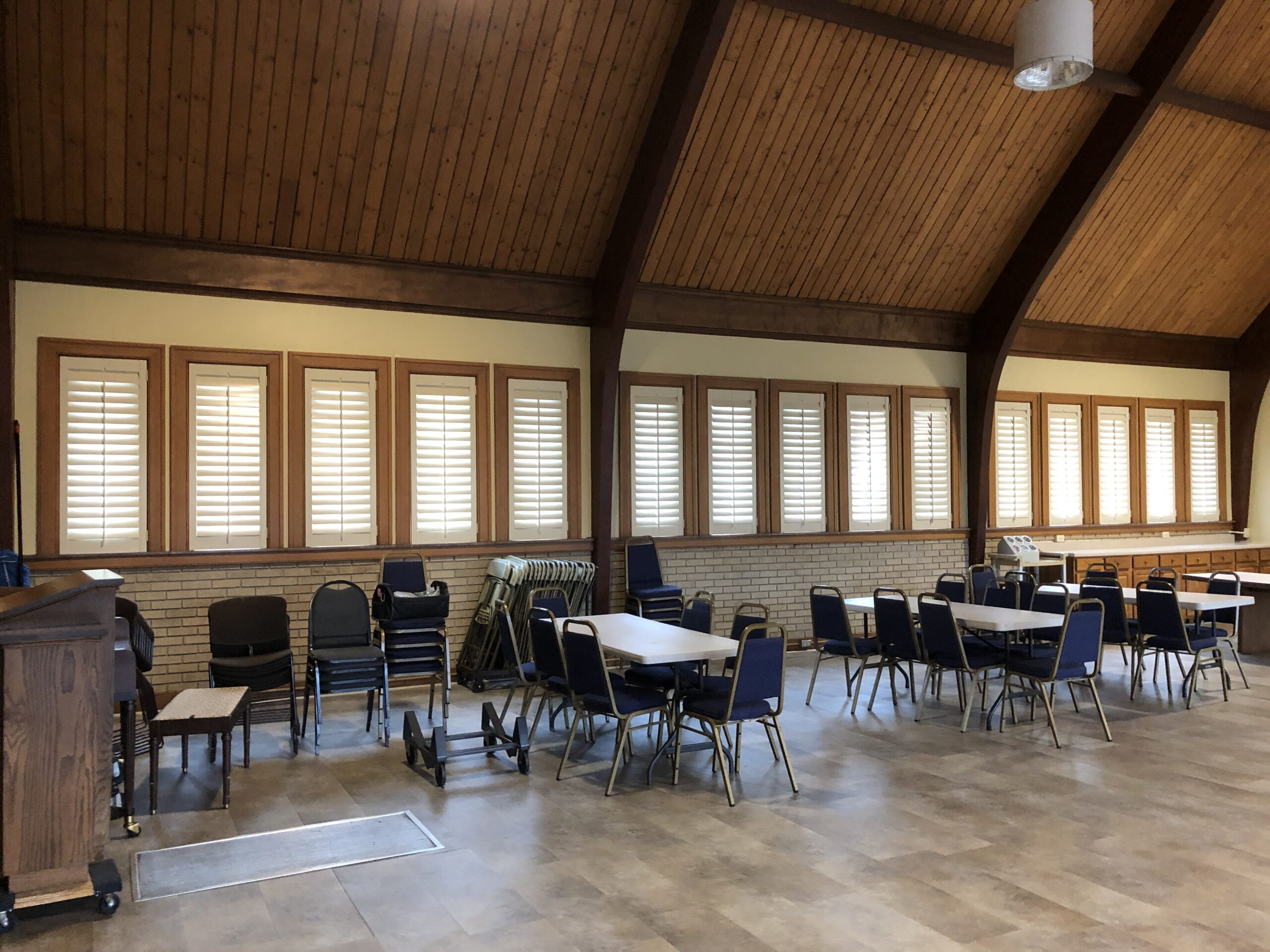 Interior view of Trinity Methodist Church in Lexington, KY, featuring white plantation shutters installed on standard-sized windows, framed by a softly lit room with warm wooden accents